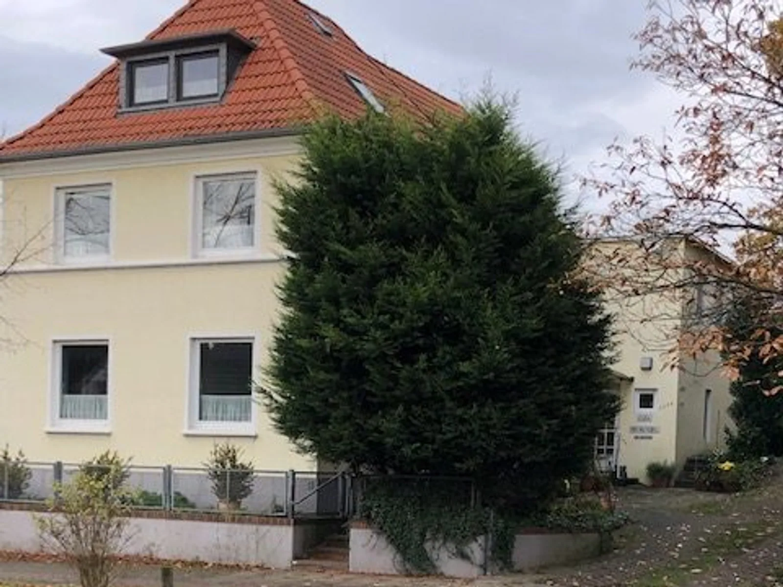 Wohnhaus mit gelbem Giebel und rotem Ziegeldach an einer ruhigen Bremer Straße, vermittelt von Weser Immobilien.